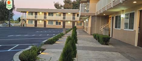 Un motel con estacionamiento, un pasillo cubierto y un letrero que dice Peach City Inn.