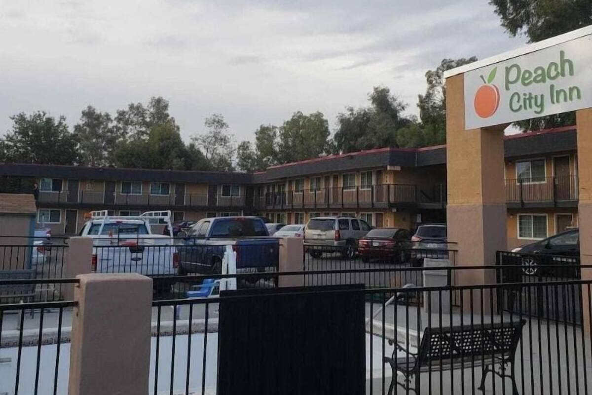 A motel with multiple buildings, a parking lot, and a sign for Peach City Inn.