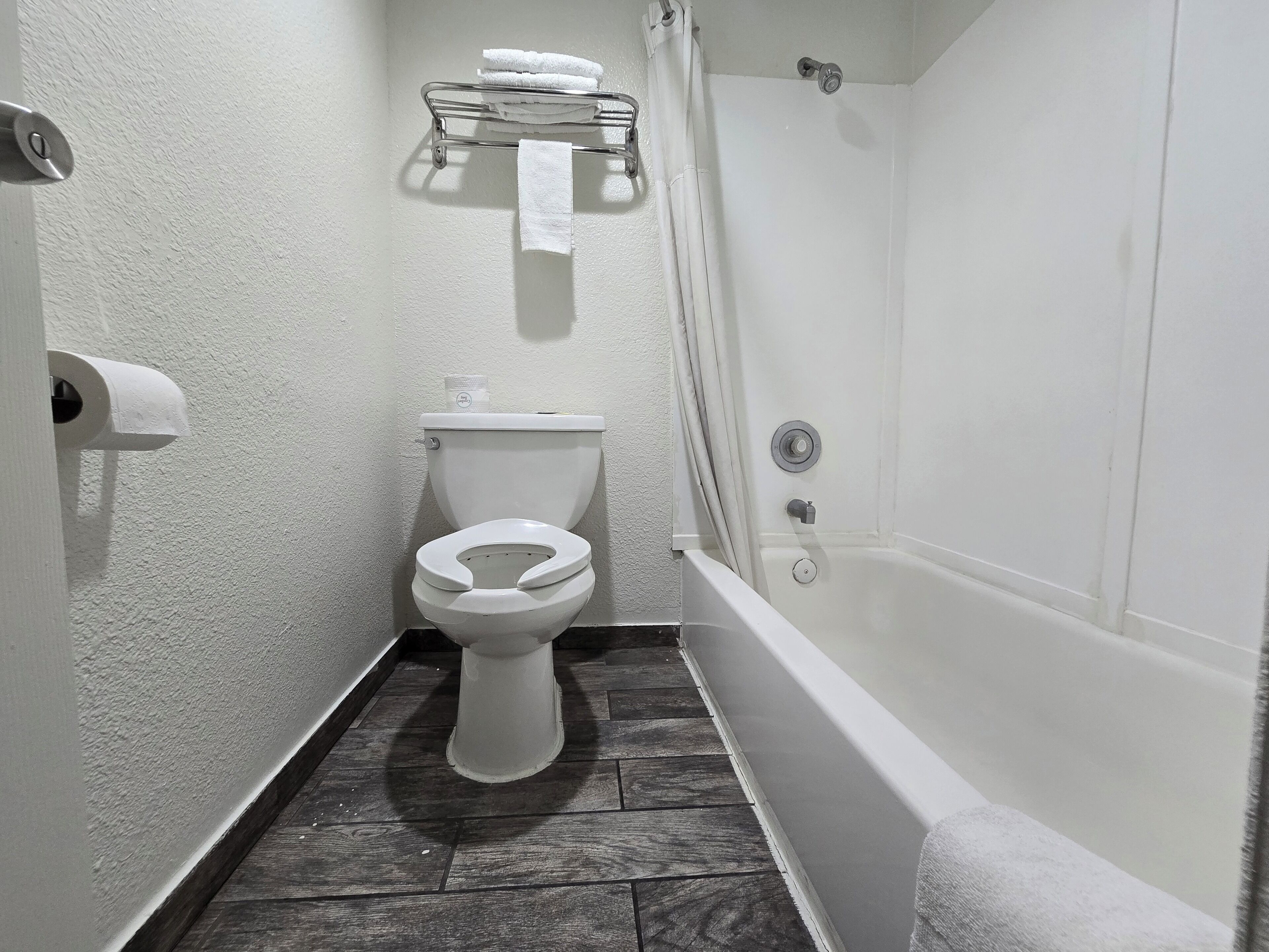 A bathroom with a toilet, a shower, and a towel rack.