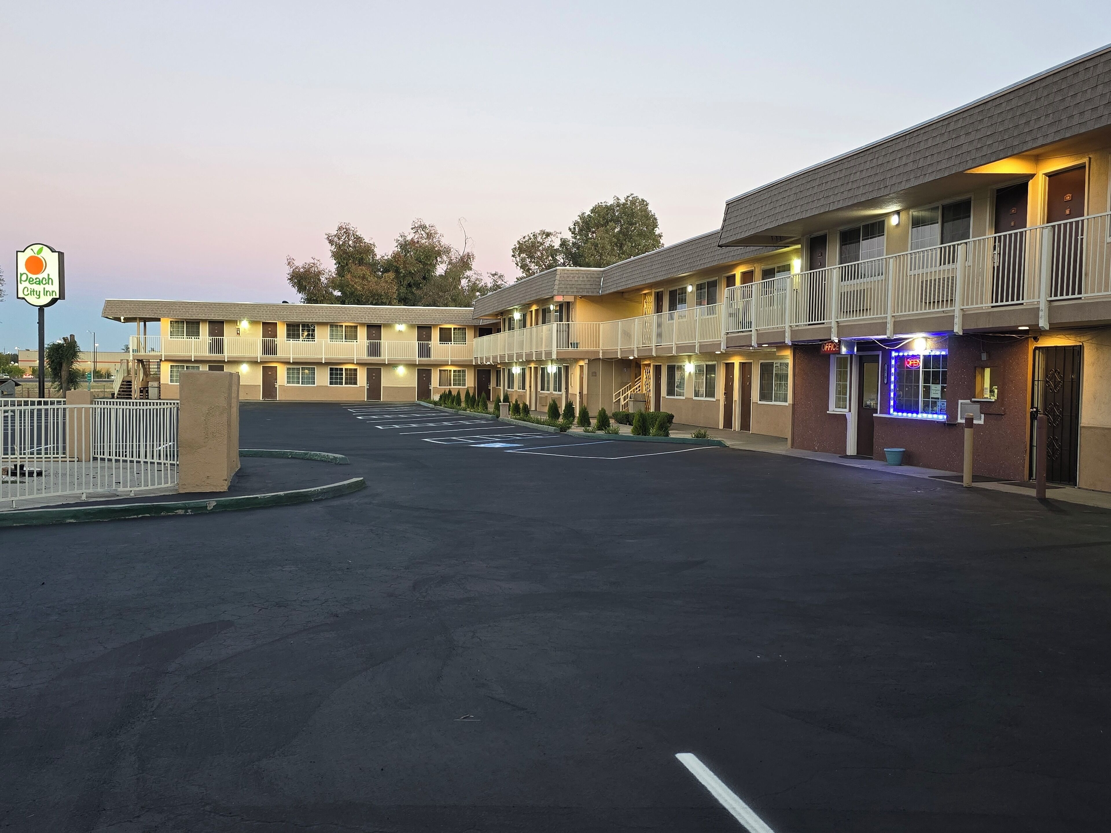 A motel with a two-story structure, a fenced parking lot, and a sign indicating it is the Peach City Inn.