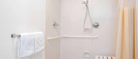 Un baño con ducha, toallero y barra de apoyo.