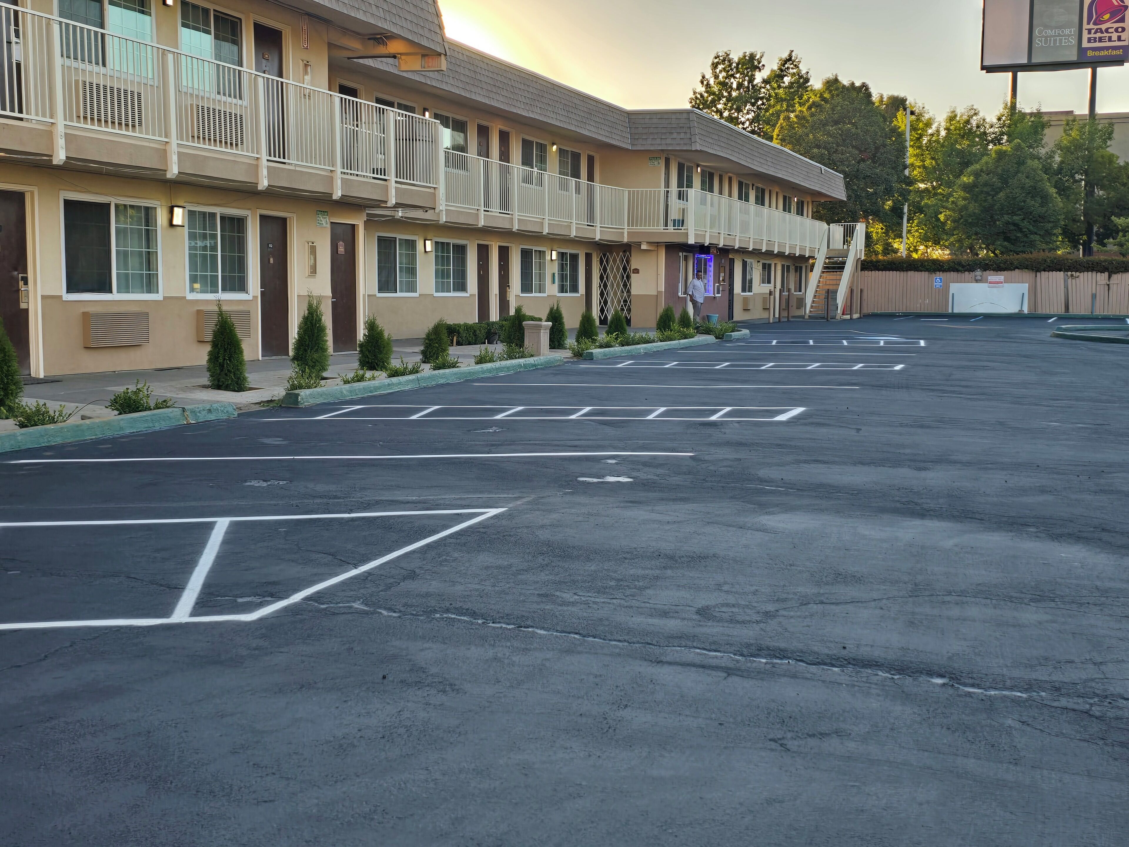 A motel with a parking lot, multiple balconies, and a sign for a breakfast restaurant.