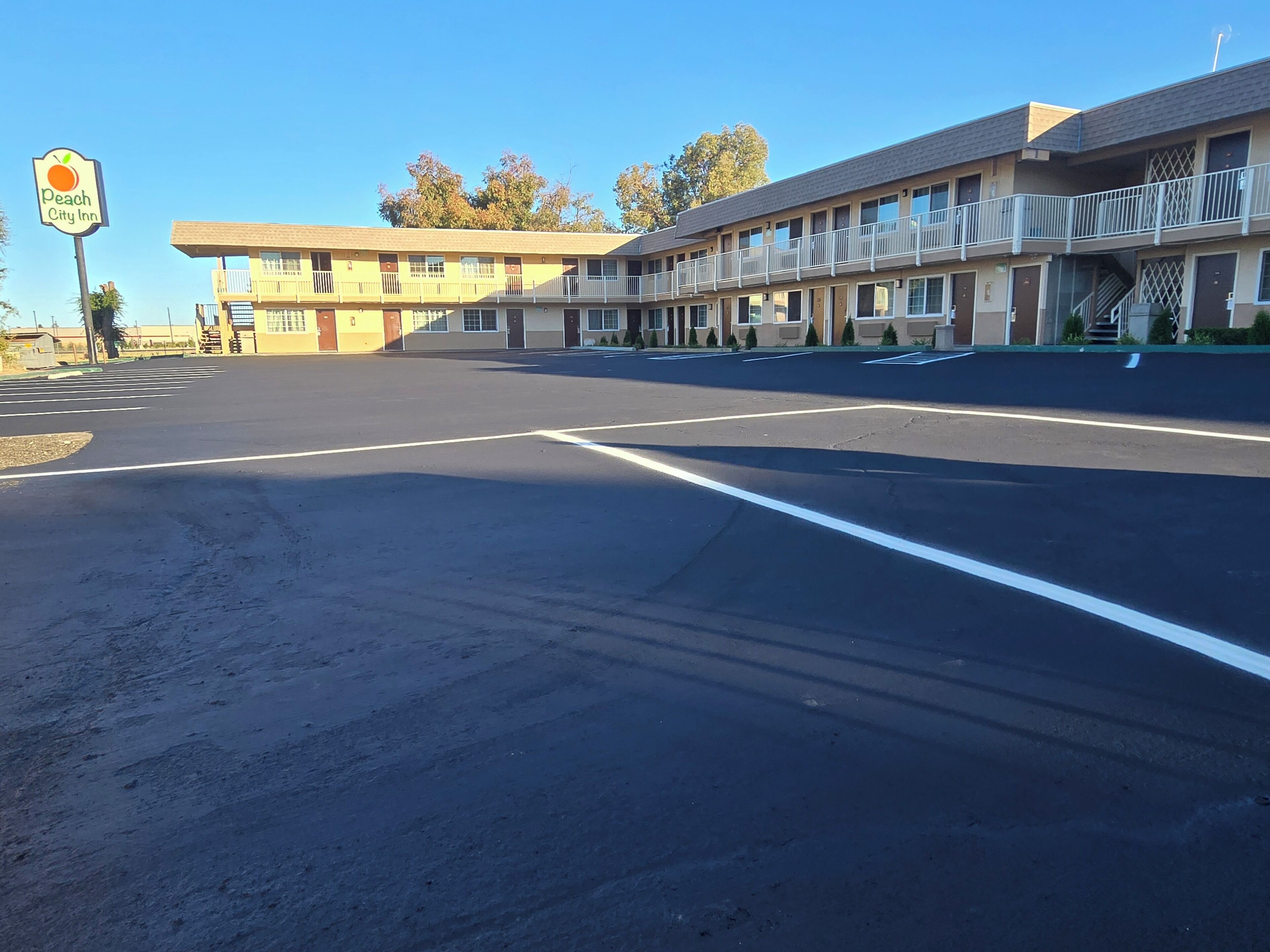 A motel with a large parking lot and a sign for Peach City Inn.