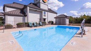 Une piscine dont la profondeur maximale est indiquée à 3 pieds, des chaises longues à proximité et un bâtiment arborant le logo Super 8.