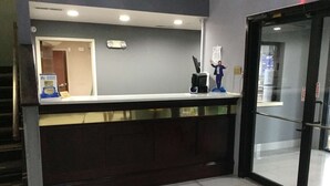 Un comptoir d’accueil doté d’une porte en verre, d’une enseigne indiquant « Meilleur hôtel selon US News », et d’une petite statue posée sur le comptoir.