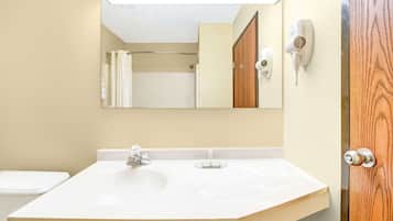 A bathroom with a white sink, a mirror, a towel rack, and a hairdryer on the wall.