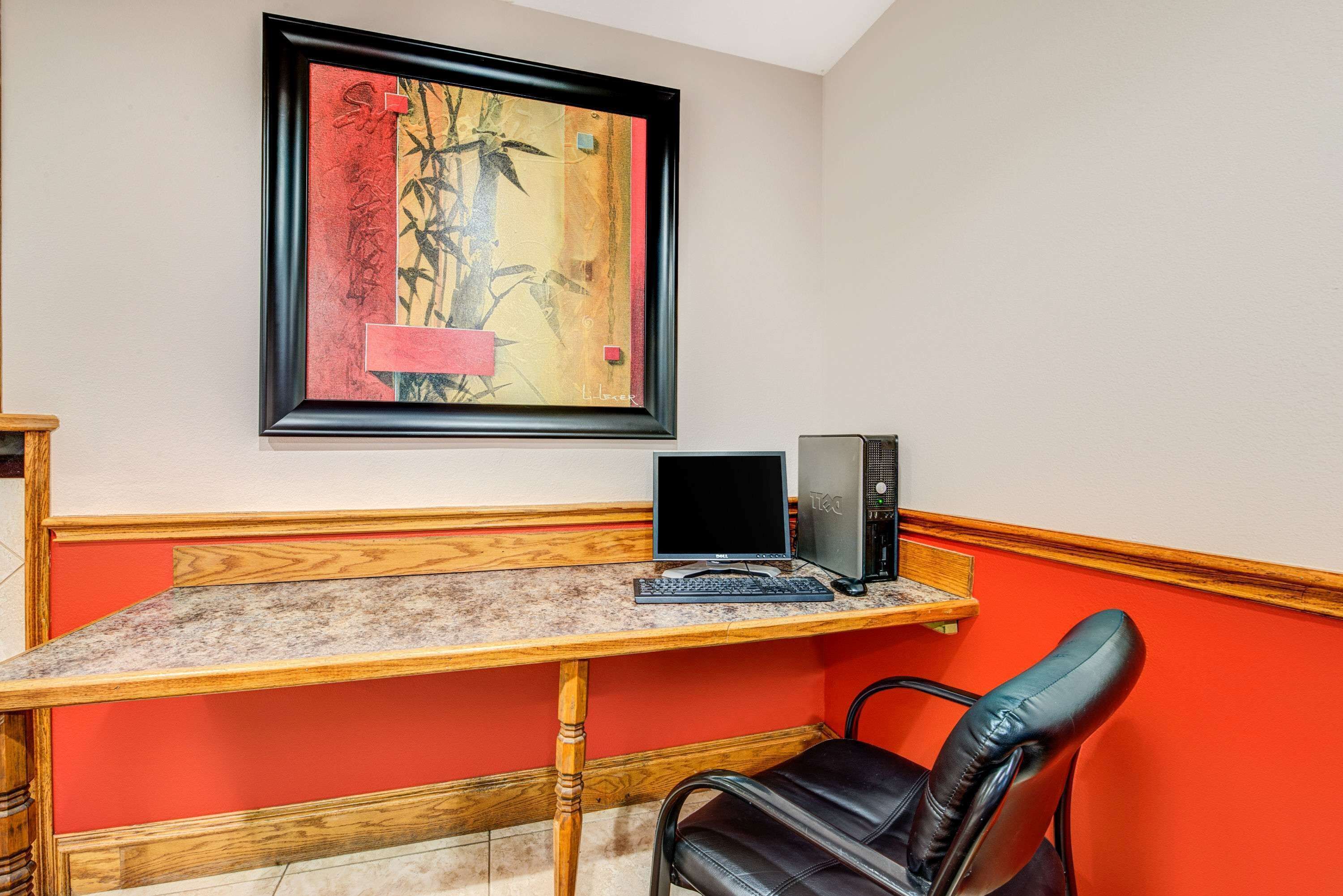 Une pièce comprenant un bureau en bois, un ordinateur, une chaise et une œuvre d’art encadrée accrochée au mur.