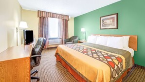 Une chambre d’hôtel avec un lit, un bureau, une chaise, une lampe et un tableau au mur.