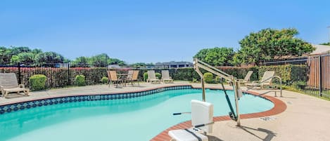 A swimming pool with a 5 ft depth marker, surrounded by lounge chairs and a brick border.