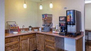 Une cuisine d’hôtel équipée d’un coin café, comprenant une machine à café, un réfrigérateur et un distributeur de céréales.