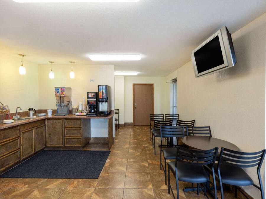 A kitchen with a coffee station, a dining area with chairs, and a TV mounted on the wall.
