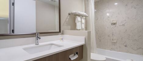 A modern bathroom with a sink, mirror, towel rack, toilet, and bathtub.