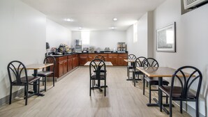 A spacious kitchen with wooden cabinets, a central island, and multiple dining tables with chairs. - Townhouse Inn (High Point)