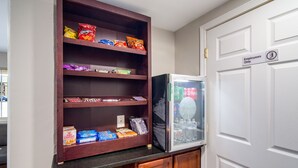 A kitchenette with a refrigerator stocked with beverages, a shelf with snacks, and a door marked "Employees Only". - Townhouse Inn (High Point)