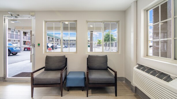 A waiting area with two armchairs and a bench, large windows with a view of the street, and a radiator on the wall. - Townhouse Inn (High Point)