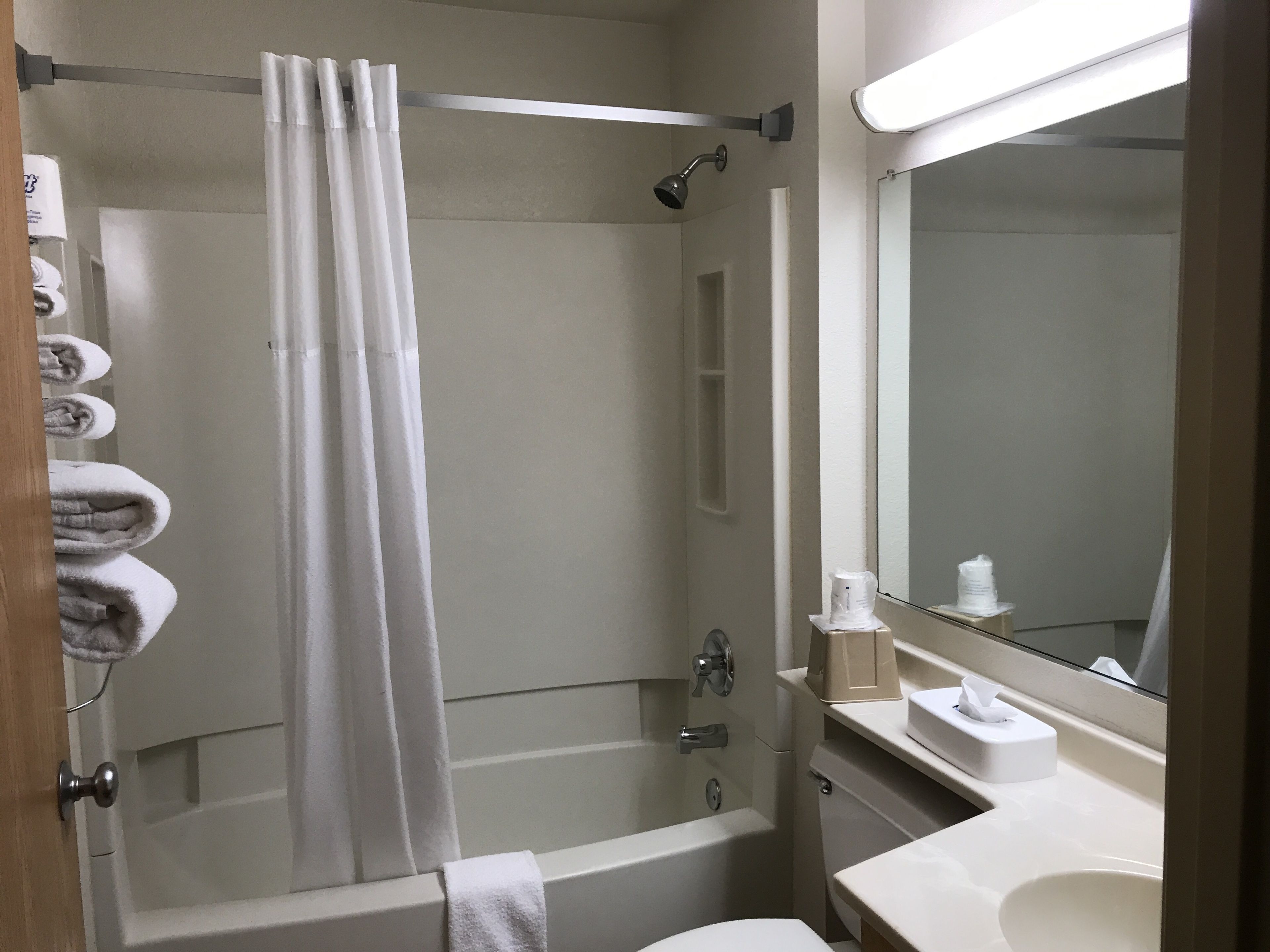 Een badkamer met een douche, toilet, wastafel en spiegel.
