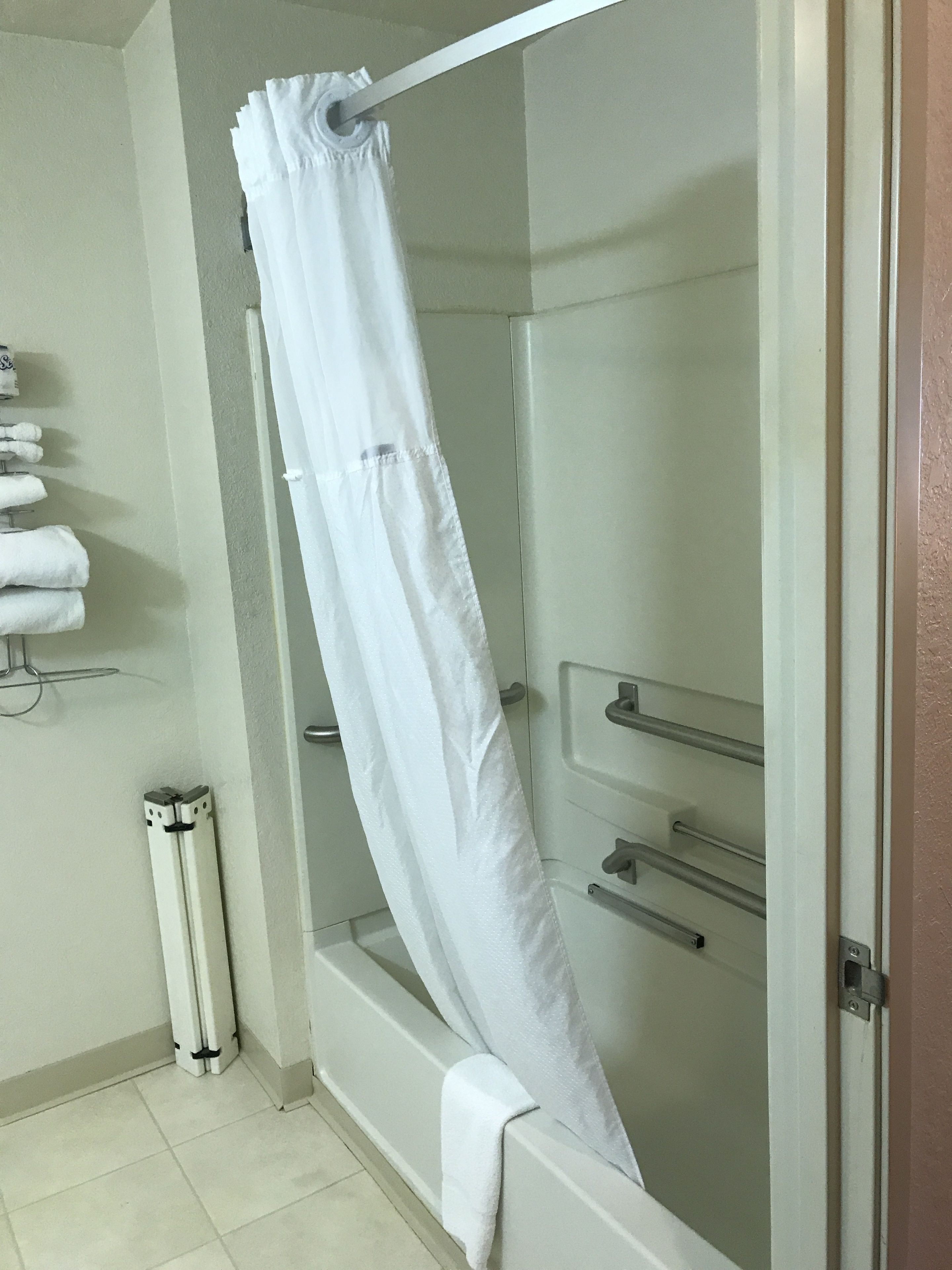 Une salle de bain avec un rideau de douche, une baignoire et un porte-serviettes avec des serviettes.