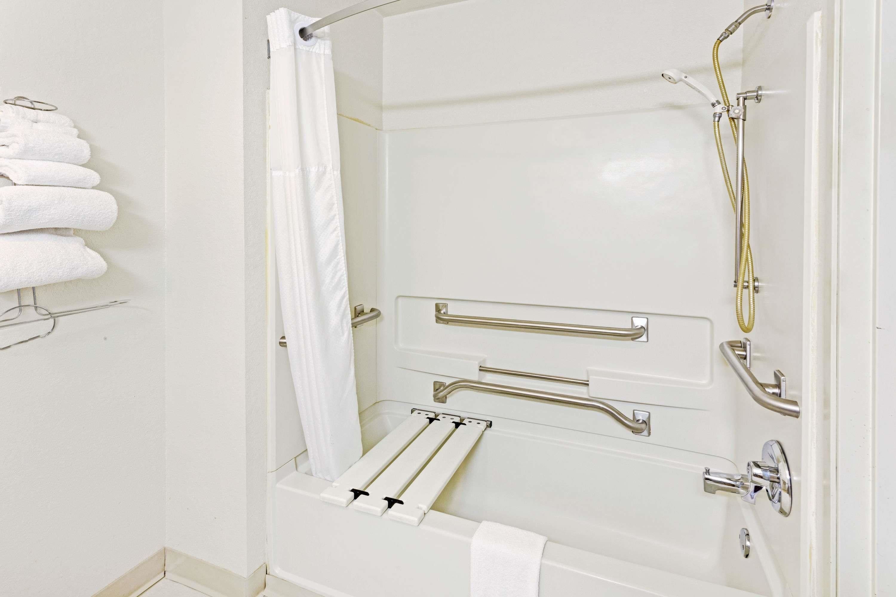 A white shower with grab bars, a towel rack, and a showerhead.