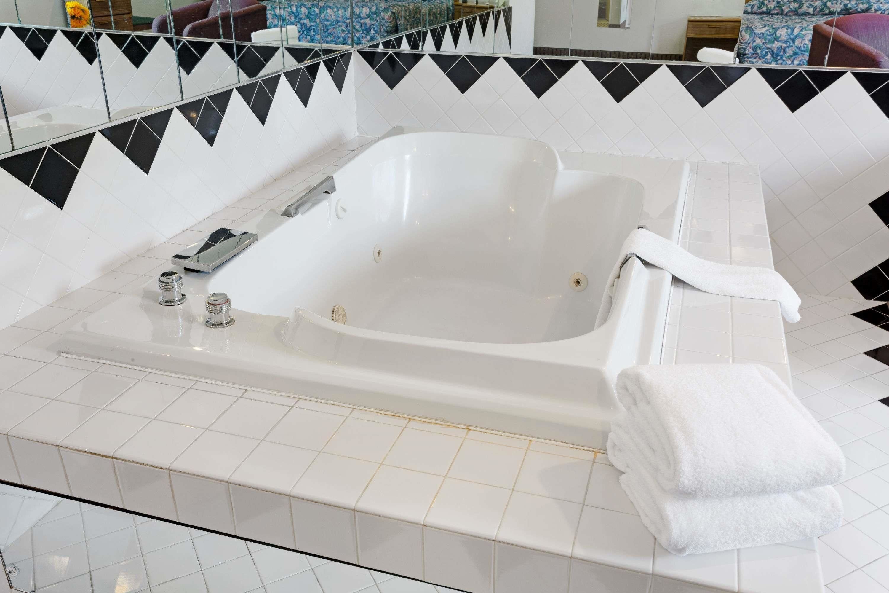 Un baño moderno con una bañera blanca, cabina de ducha con paredes de cristal y suelo de baldosas.
