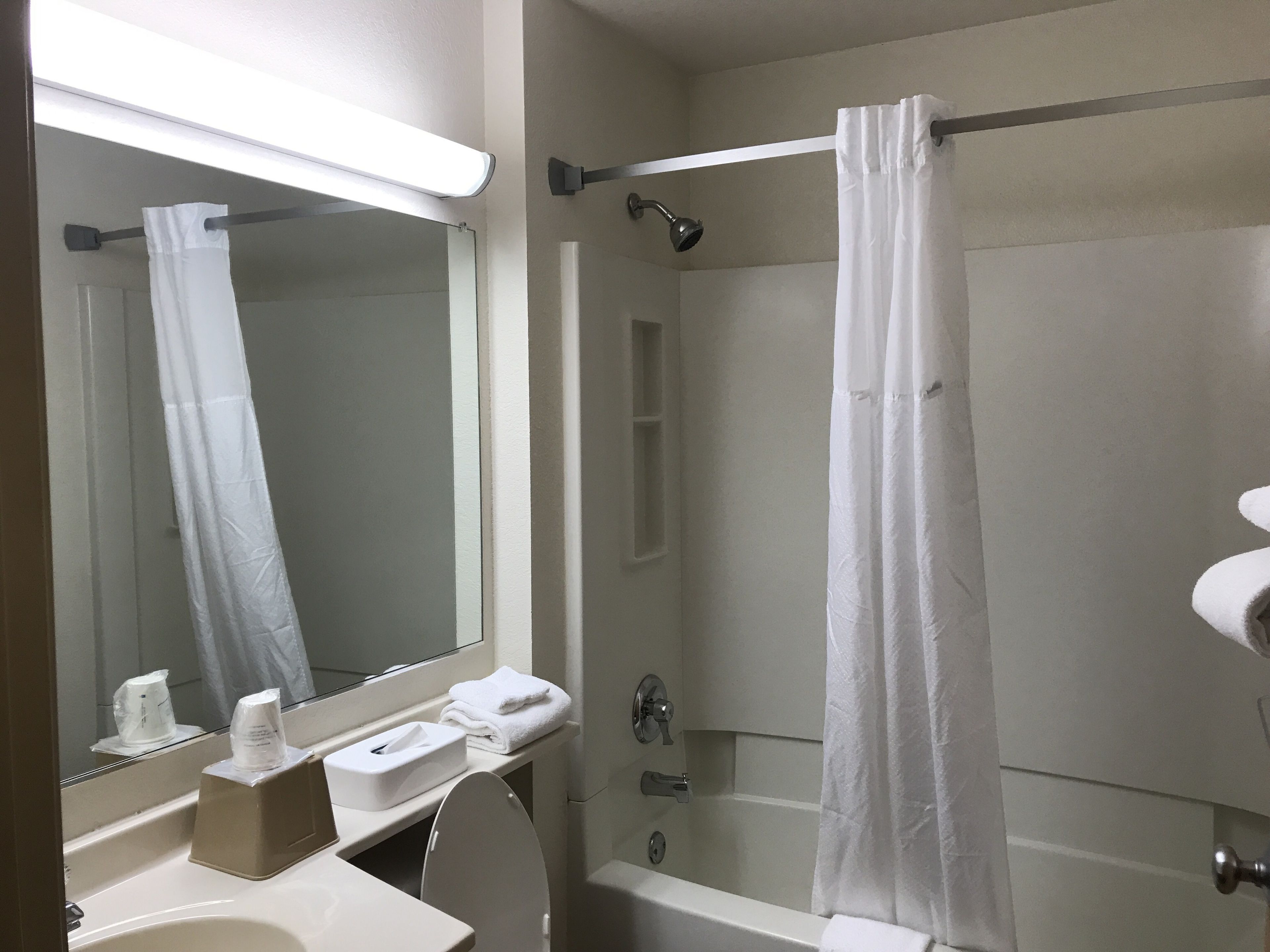 A bathroom with a toilet, sink, mirror, shower curtain, and a bathtub.