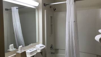 A bathroom with a toilet, sink, mirror, shower curtain, and a bathtub.