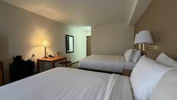Une chambre d’hôtel avec deux lits, un bureau avec une lampe, une chaise et un téléviseur.