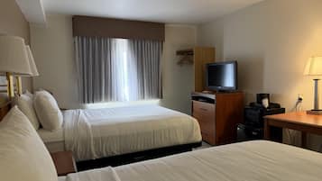 Habitación de hotel con dos camas, televisión, escritorio y cómoda.