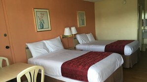 A hotel room with two beds, a desk, and chairs. - Americas Best Value Inn Tucker (Tucker)