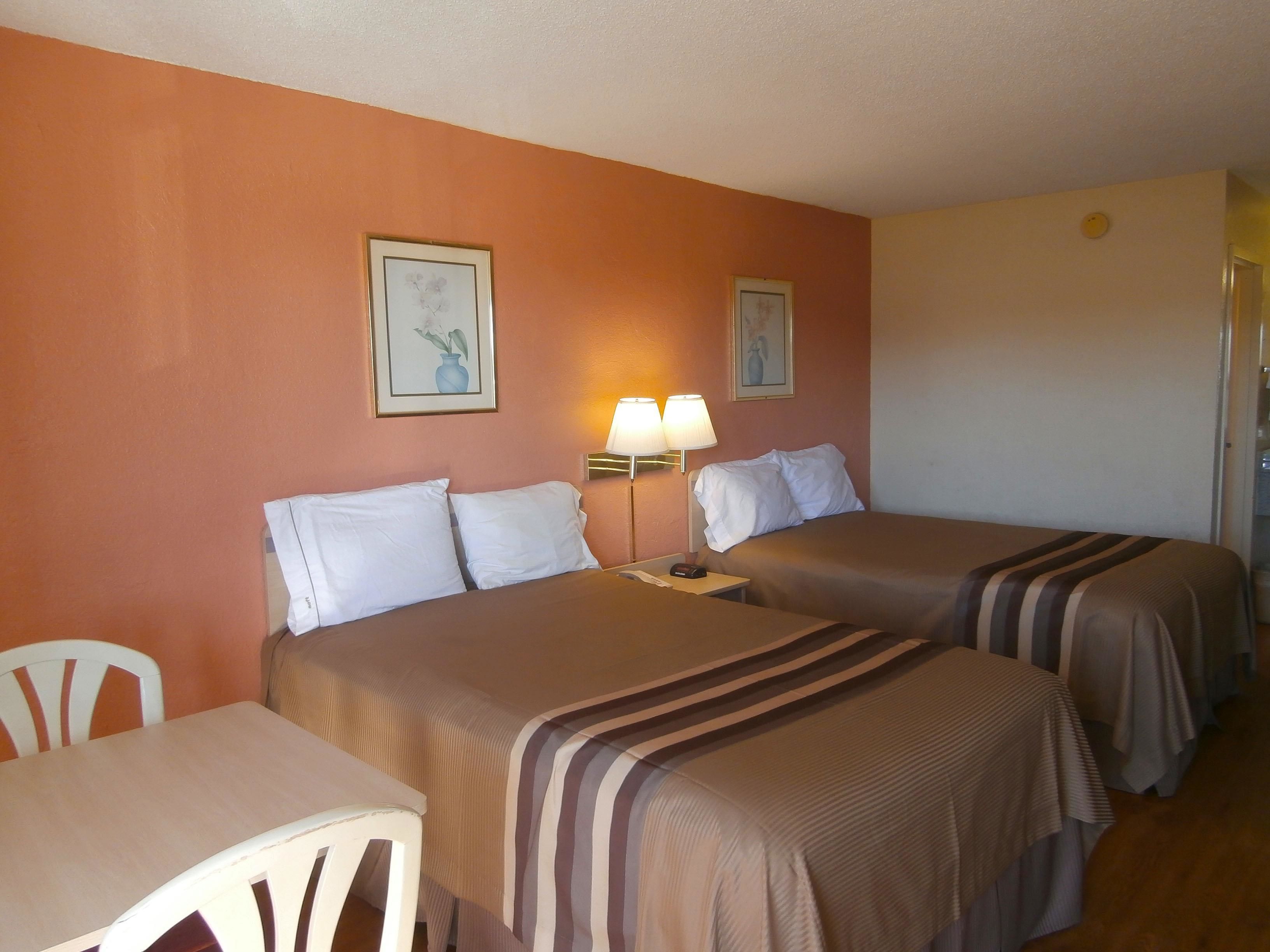 Una habitación de hotel con dos camas, un escritorio y dos lámparas.