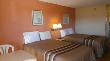 Una habitación de hotel con dos camas, un escritorio y dos lámparas.