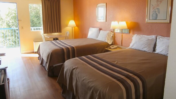 A hotel room with two beds, a desk, a chair, a phone, and a window with curtains. - Americas Best Value Inn Tucker (Tucker)