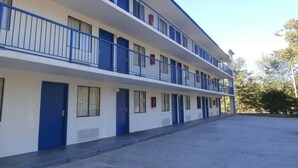 A multi-story motel with blue railings and doors, a flat roof, and a parking lot in front. - Americas Best Value Inn Tucker (Tucker)