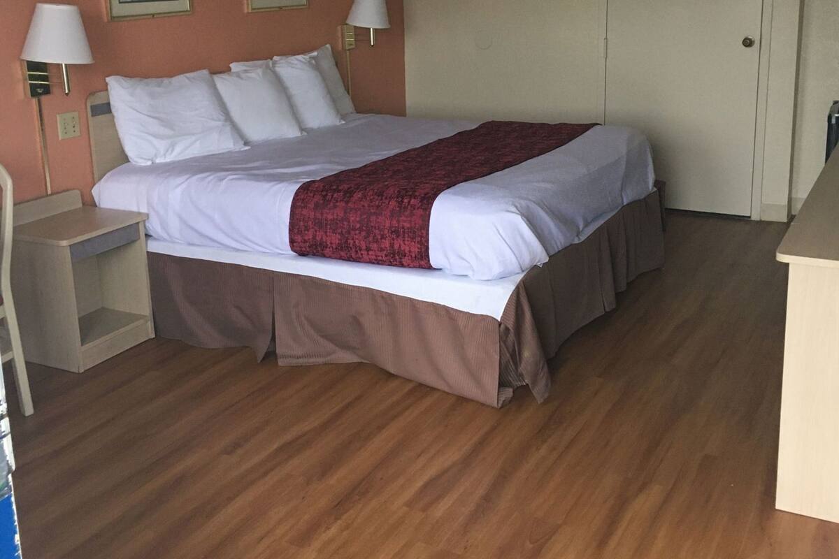A hotel room with a bed, bedside tables, a door, and two wall-mounted lamps.