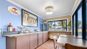 Una cocina moderna con barra desayunadora, un ventanal grande y un comedor con mesa y sillas.
