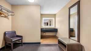 Un baño de hotel con banca, espejo y lavamanos.
