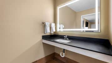 A modern bathroom with a black countertop, white sink, and a large mirror with built-in lighting.