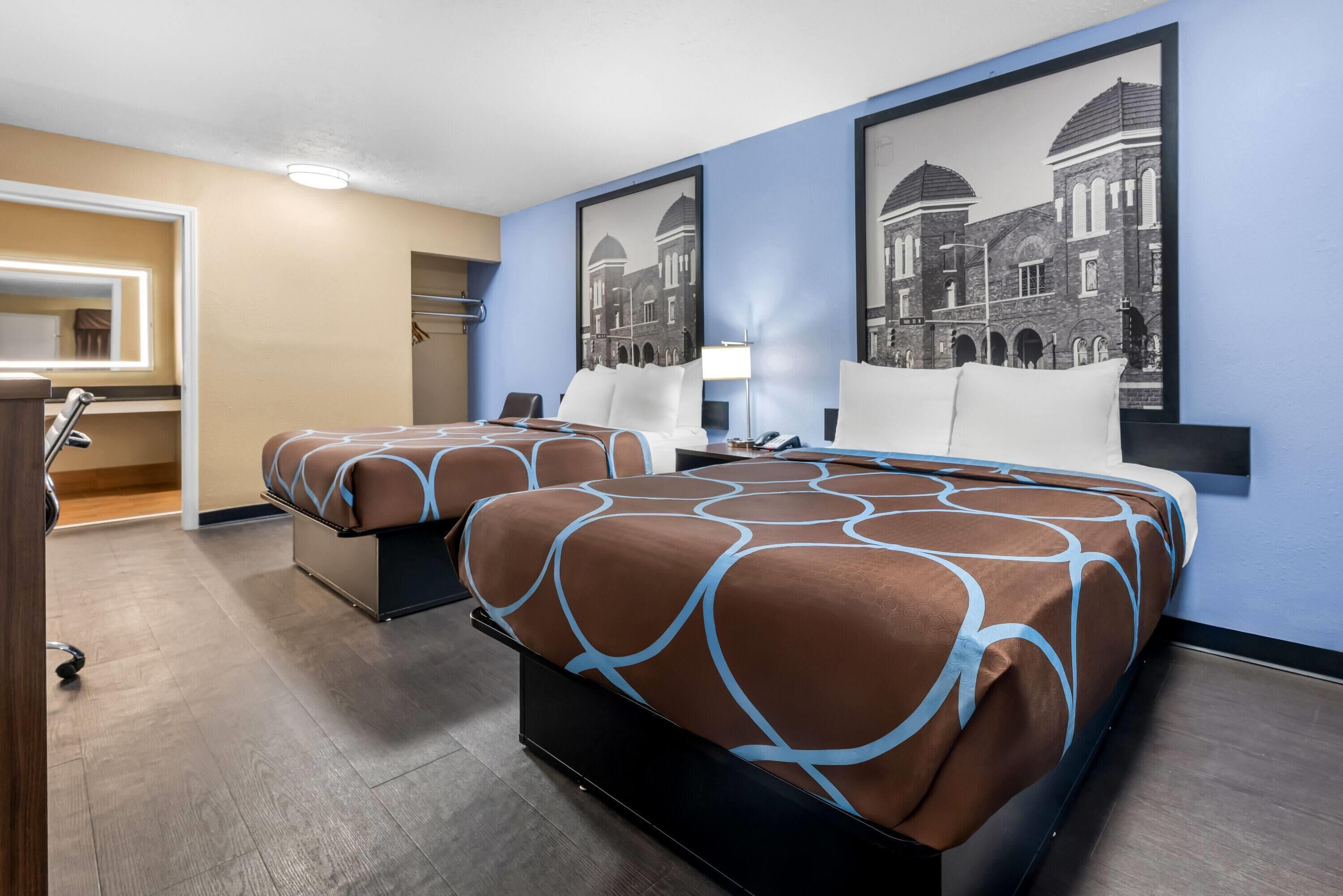 A hotel room with two beds, a bathroom, and a hallway.