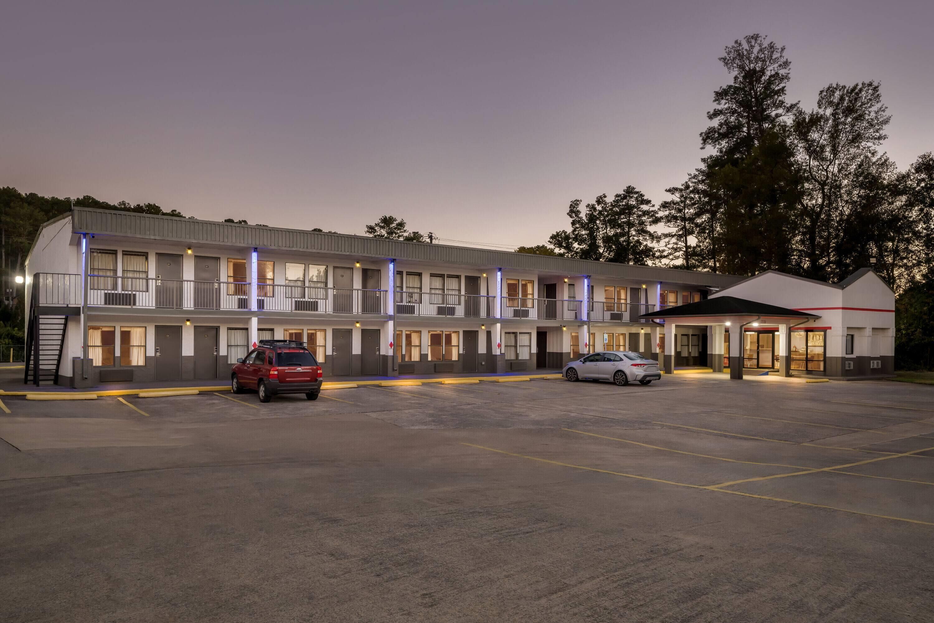 A motel with multiple rooms, a parking lot, and a small building with a red roof.