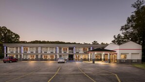 Un hotel de varios pisos con estacionamiento, una entrada cubierta y un edificio con techo plano.