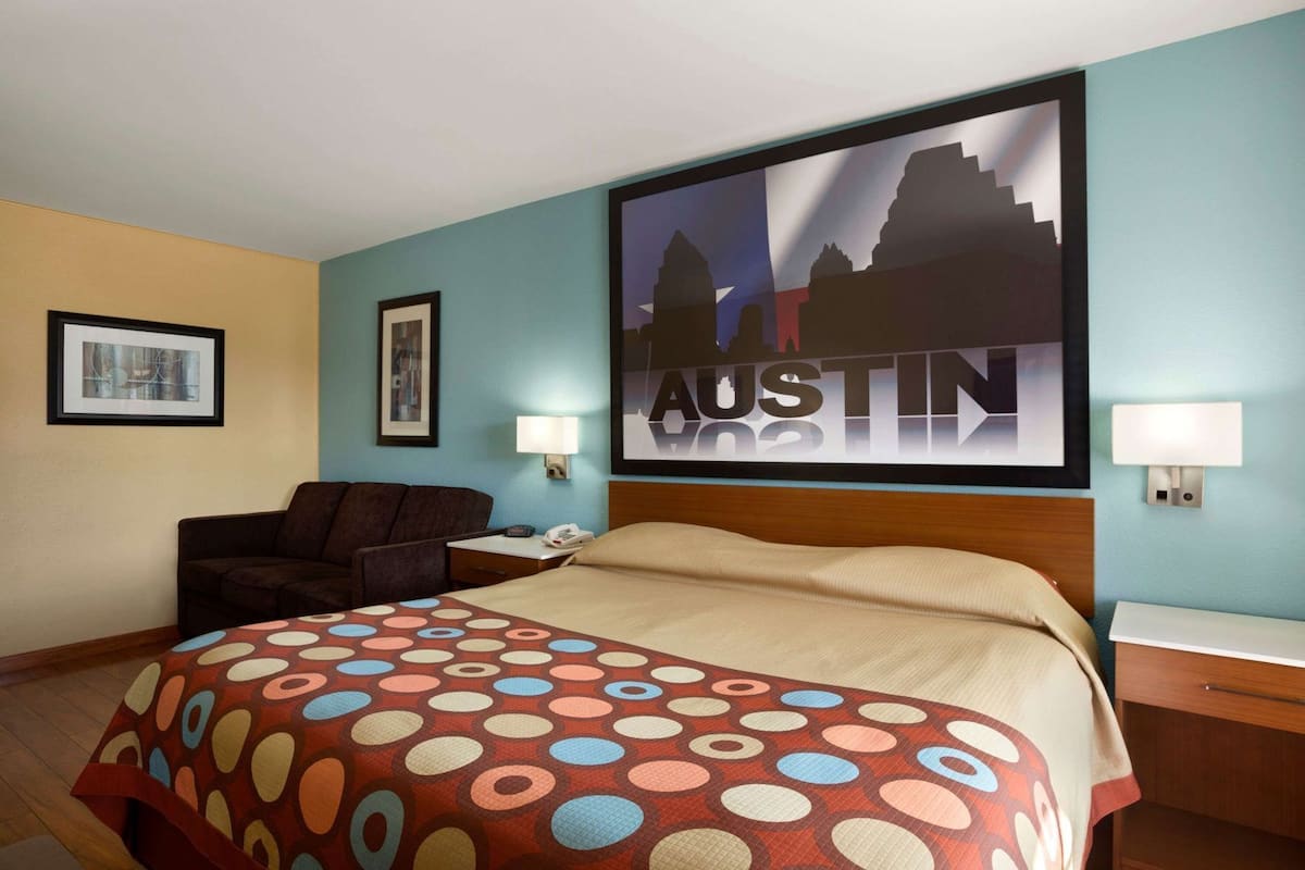 Una camera d'albergo con un letto, una scrivania, una sedia e un murale raffigurante un panorama cittadino.