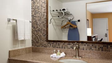 A bathroom with a granite countertop, a sink, a towel rack, a mirror, and a towel hanging on the wall.