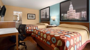 Habitación de hotel con dos camas, un escritorio, una silla, un televisor y cuadros en la pared.