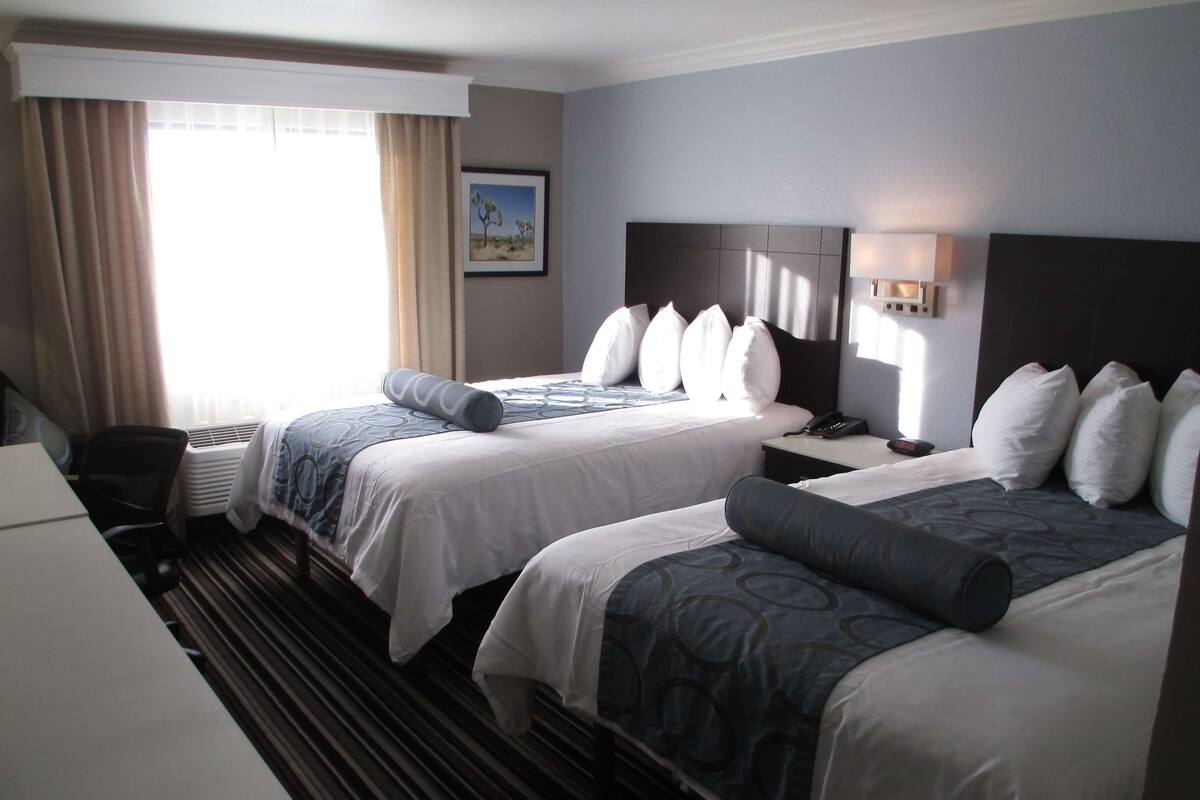 Une chambre d’hôtel avec deux lits, un bureau et une chaise.