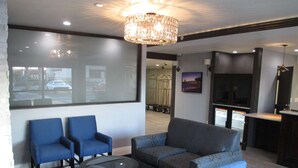 A modern living room with two blue armchairs, a grey sofa, a glass coffee table, and a chandelier. - Best Western Plus Diamond Valley Inn (Hemet)