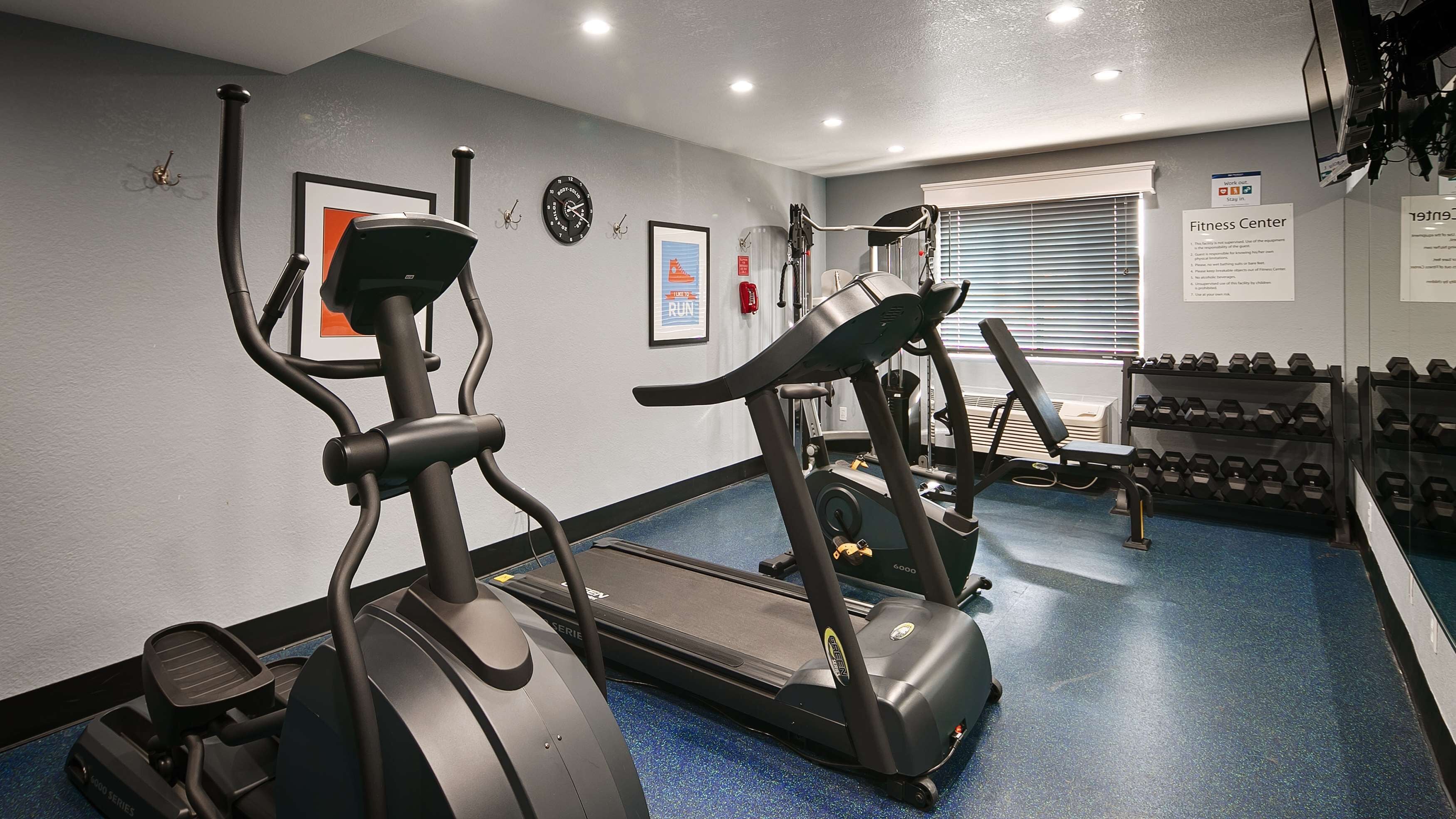 A fitness center with treadmills, elliptical machines, and a rack of dumbbells.