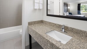 Une salle de bain moderne avec un comptoir en granit, un lavabo blanc et un grand miroir.