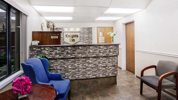 A reception area with a stone wall, a blue chair, a wooden desk, and a vase of flowers.