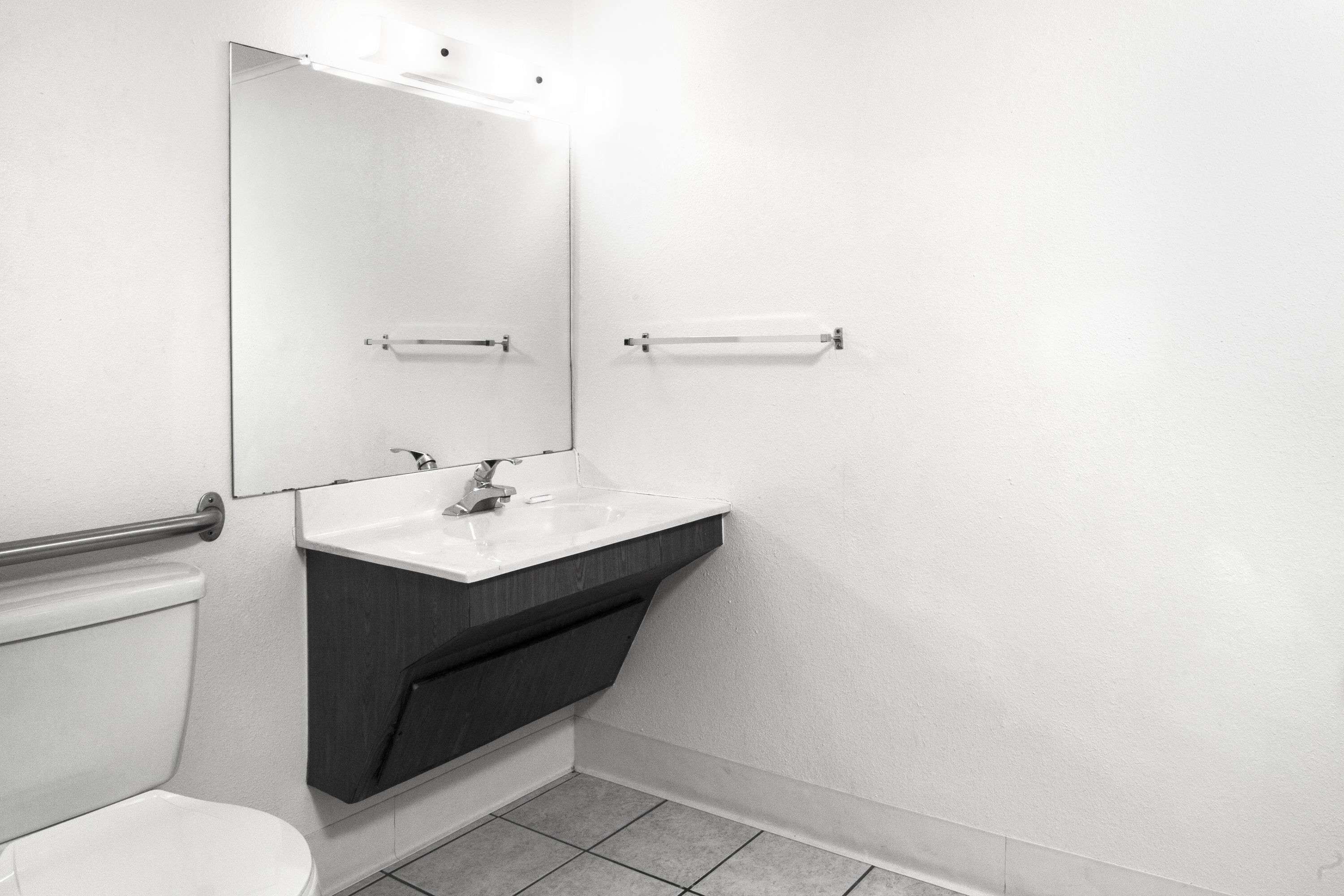 A modern bathroom with a white sink, dark vanity, and a large mirror.