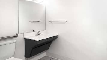A modern bathroom with a white sink, dark vanity, and a large mirror.