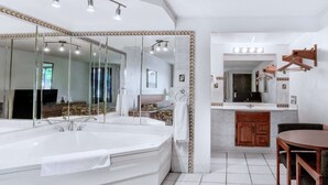 A modern bathroom with a large bathtub, a vanity with a mirror, and a wooden chair.